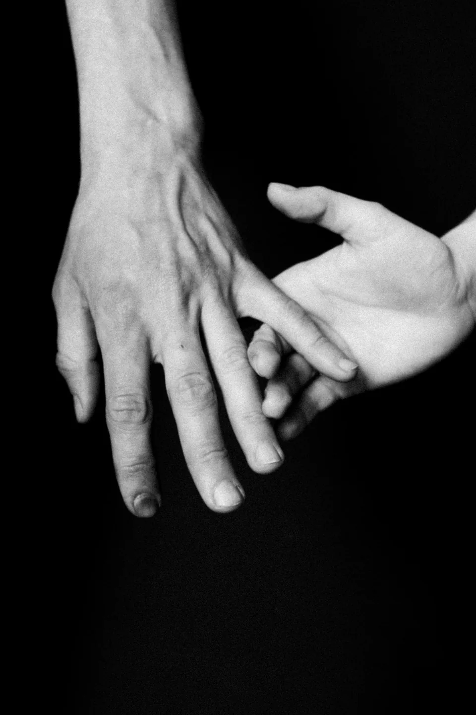 Gros plan en noir et blanc de deux mains qui se touchent doucement