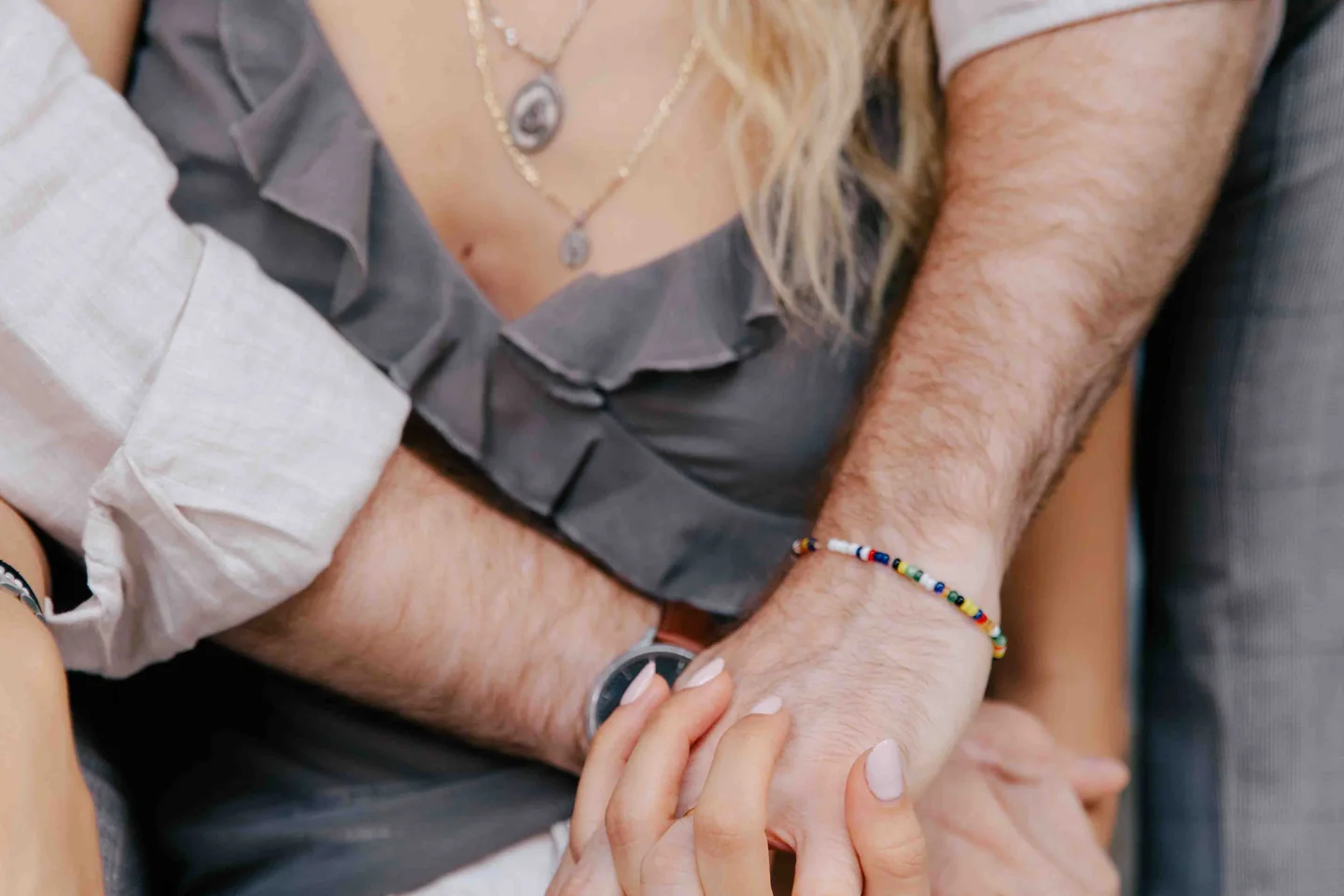 Gros plan d’un couple enlacé : les mains de la femme reposent sur l’avant-bras de son partenaire